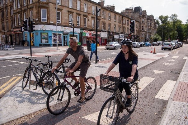 Two cyclists travel together on a segregated cycle path