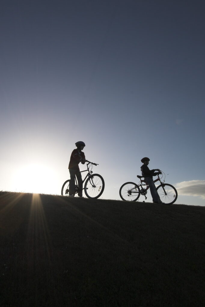 Two cyclists take in the sea view, silhouetted against the late summer sun in Aberdeen, NCR 1